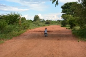 child riding bike on red dirt road