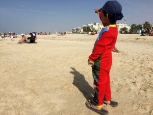 boy from behind pointing at high rises at Jumeira Beach